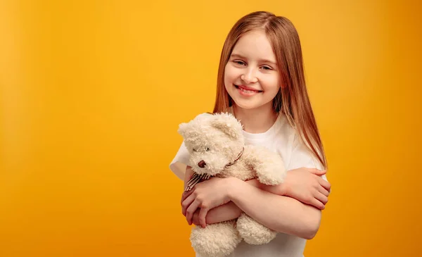 Meisje met teddybeer geïsoleerd op gele achtergrond — Stockfoto