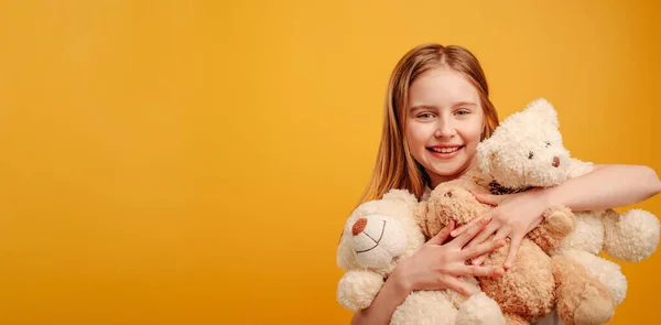 Menina com ursinho isolado no fundo amarelo — Fotografia de Stock