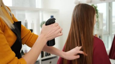 Kuaför müşterinin saçını spreyliyor.