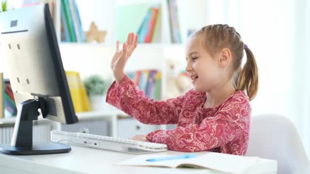 Маленькая девочка машет в веб-камеру во время урока — стоковое видео