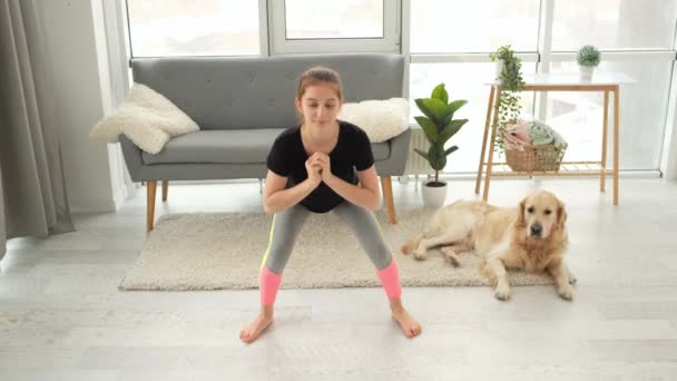 Chica haciendo sentadillas con golden retriever perro — Vídeos de Stock