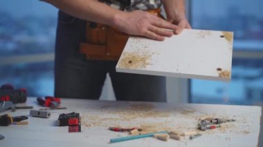 Adam tahtadaki talaşları silkeliyor.