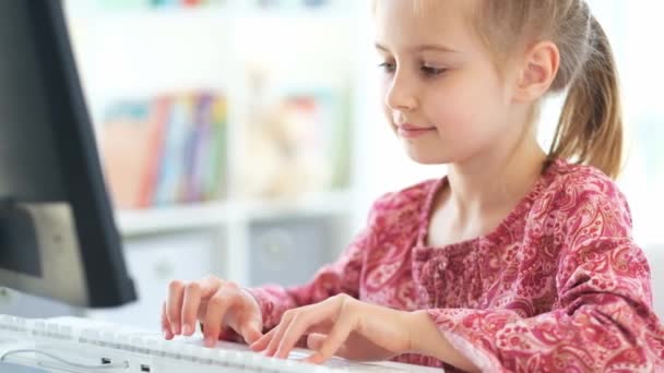 Chica de la escuela escribiendo en el teclado en el escritorio — Vídeo de stock
