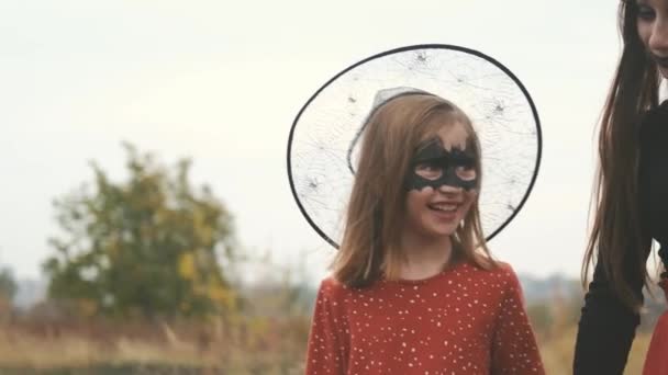 Дівчата в костюмах Хеллоуїна ходять тримаючи руки — стокове відео