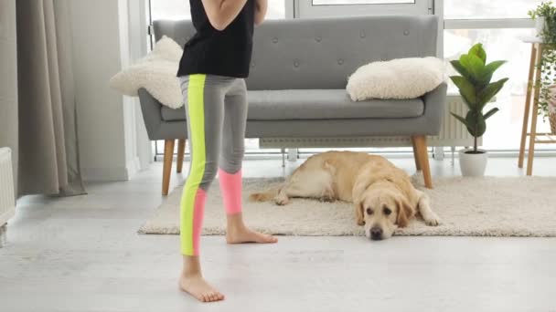 Flicka gör knäböj med golden retriever hund — Stockvideo