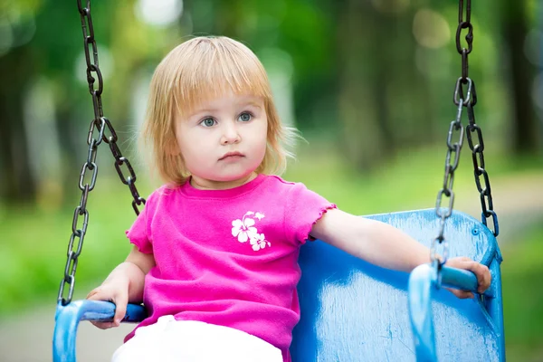 Kleines Mädchen schaukelt auf Spielplatz — Stockfoto