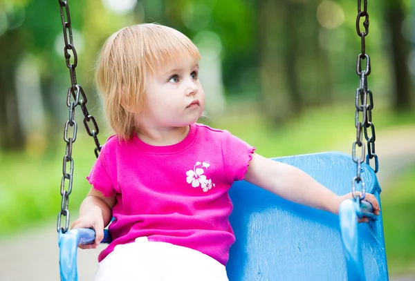 Little girl swinging on playground — Stock Photo, Image
