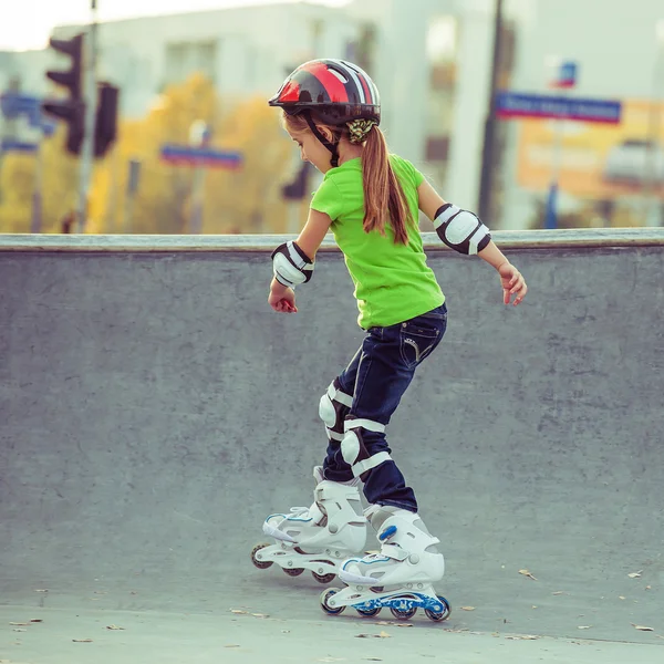 Вид сзади на девочку в шлеме на роликовых коньках в парке — стоковое фото