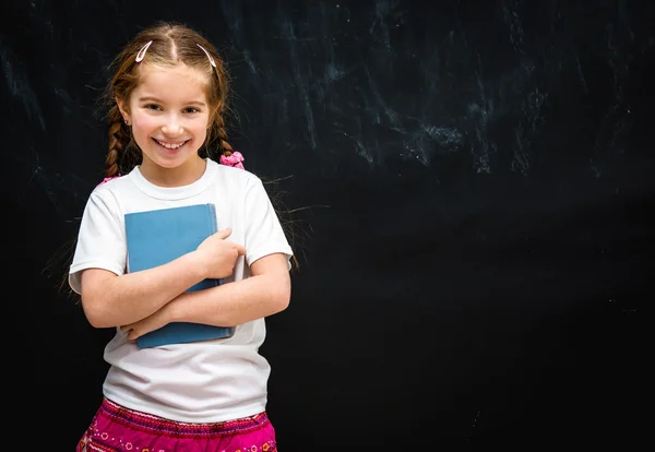 Klein meisje op zwart schoolbord achtergrond — Stockfoto