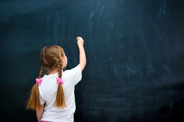 Klein meisje tegen schoolbord — Stockfoto