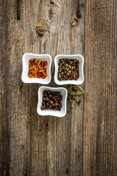 Different kinds of pepper in bowls — Stock Photo, Image