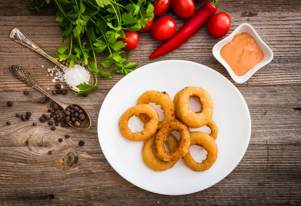 Aros de cebolla en el plato con salsa y verduras —  Fotos de Stock