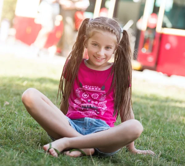 Malá dívka sedící trávě — Stock fotografie