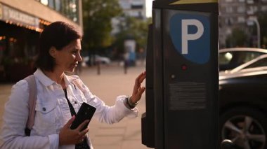 Şehir caddesinde bir park metrenin plakasını yazan bir kadın.