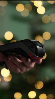 Bulanık bir Noel arka planına karşı Pos Terminali 'ndeki Kadın El Ödemeleri, Dikey Video