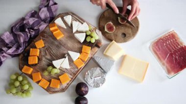 Peynir tahtası için incir kesen bir kız, mutfak masasının üstünden görünüyor.