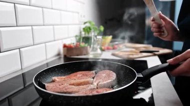 Mutfak ocağında kırmızı somon kızartmak tüm aile için sağlıklı yemekler pişirmek.
