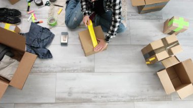 Kız karton kutuları paketliyor ve onları eve teslim etmek için hazırlarken bantla kapatıyor.