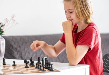 Düşünceli, sevimli küçük kız satranç oynuyor, harekete geçmeye hazır.