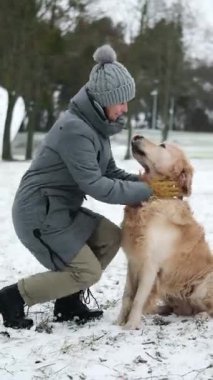 Golden Retriever Dog sahipleriyle oynarken küçük bir kız ve annesi sevimli bir köpekle, dikey bir videoyla eğleniyor.