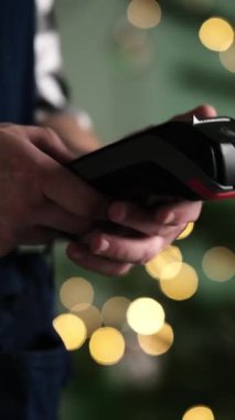 Noel boyunca bir restoranda kablosuz fatura ödemesi için akıllı telefonu kullanan kız, dikey video