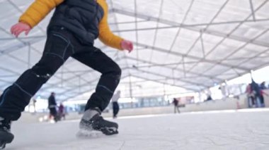 Buz pateni yapan adam kar bulutunu tekmeliyor ve düşük açılı bir bakış açısıyla buz pateni pistinde kırılıyor.