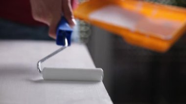 Kız ahşap bir tahtayı yakın çekim görüntüsünde beyaza boyamak için tekerlekli sandalye kullanıyor.