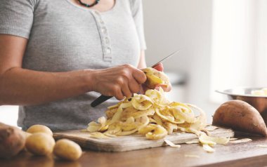 Akşam yemeğinde çiğ patates soyan bir kadın.