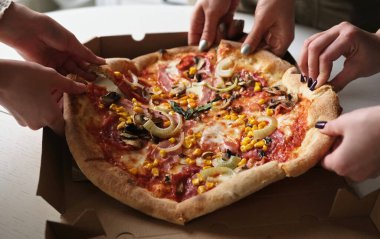 Eller kutudan pizza alıyor, aile pizza yiyor.