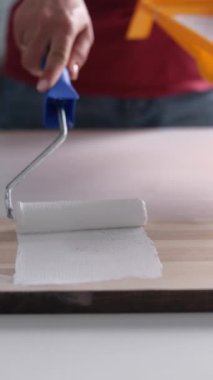 Evdeki tahta tahtayı beyaza boyamak için patenci kullanan kız, dikey video