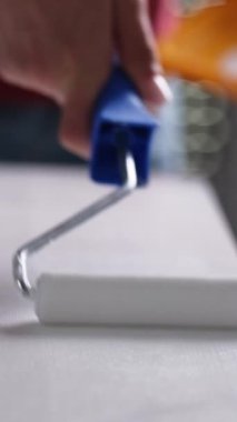 Beyaz boyalı, dikey bir video ile tahta bir tahtayı fırçalamak için paten kullanan bir kız.