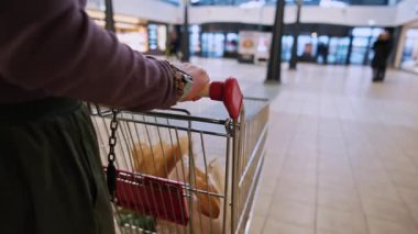 Markette alışveriş arabasıyla alışveriş yapan bir kadın.