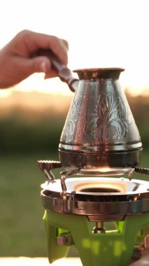 Cezve ısıtma suyuyla sabah kahvesi yapan kız portatif gaz ocağında, dikey video.