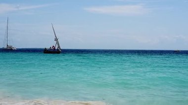 Küçük bir balıkçı teknesi güneşli bir günde kıyıda dalgalar arasında dolaşır.