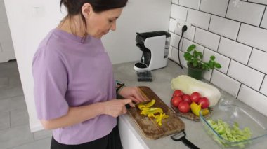 Mutfakta sebze salatası için kesim tahtasında biber doğrayan kız.