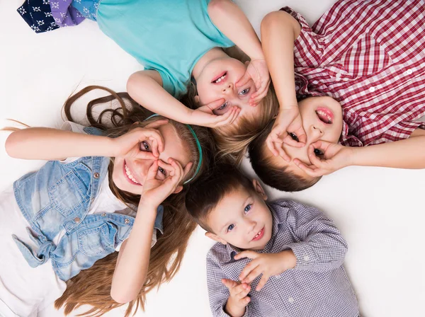 Niños tumbados en el suelo con las manos imitando gafas —  Fotos de Stock