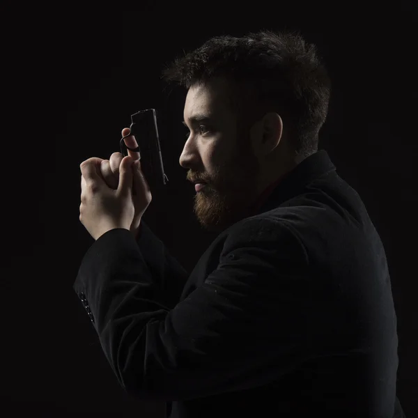 Joven serio sosteniendo pistola mirando a la izquierda — Foto de Stock