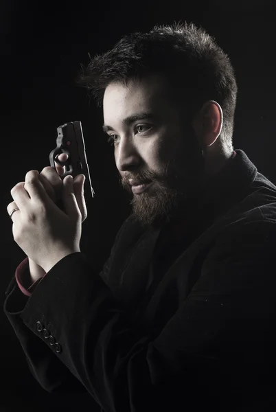 Hombre de la perilla en traje negro sosteniendo pistola pequeña — Foto de Stock