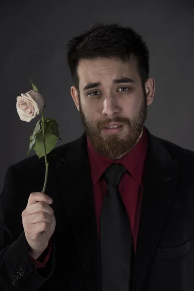 Triste hombre con desgaste formal sosteniendo rosa marchita — Foto de Stock