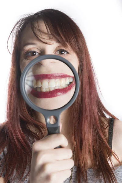 Giovane donna ingrandendo sorriso con lente d'ingrandimento — Foto Stock