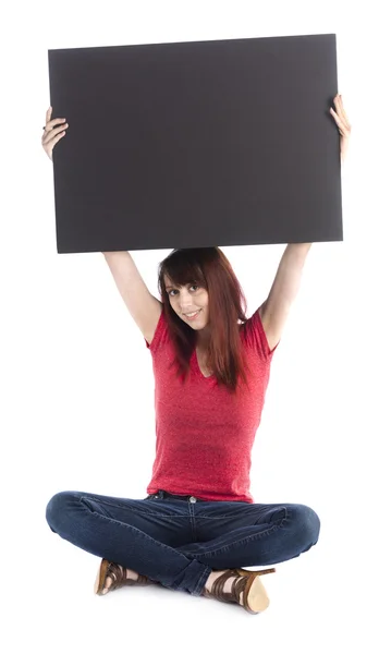 Genç kadın boş siyah karton yükselterek oturan — Stok fotoğraf