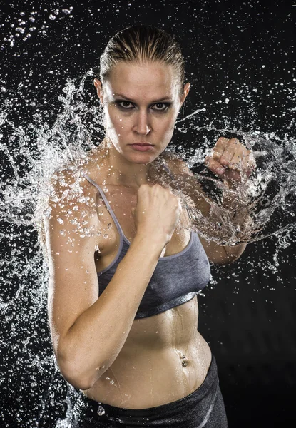 Sportliche Frau in Kampfpose in Wasserspritzern — Stockfoto