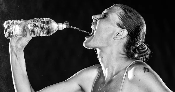 Sedienta mujer deportiva bebiendo agua de una botella — Foto de Stock