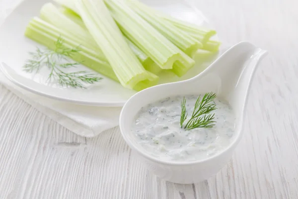 Palitos de apio fresco con salsa de yogur sobre fondo de madera blanca —  Fotos de Stock