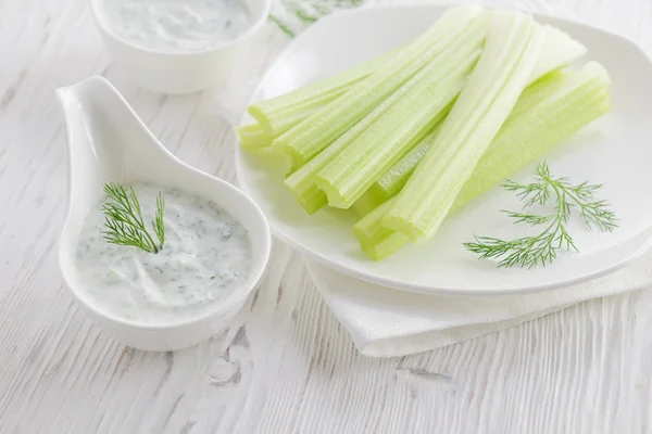 Fresh celery sticks with yogurt dip on white wooden background Stock Photo