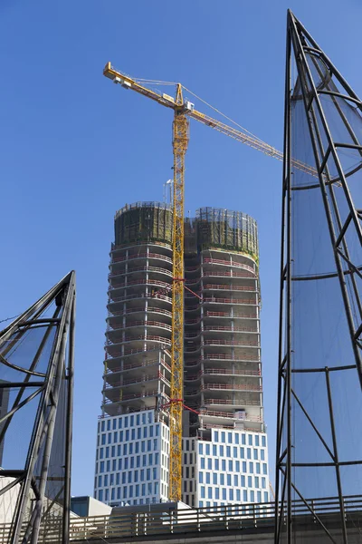 Skyscraper under construction with high crane and metal construction in the foreground