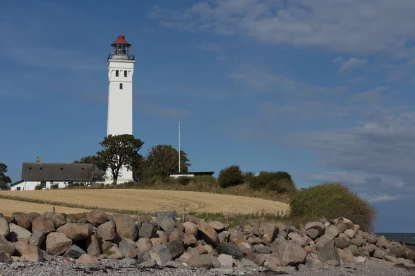 Lighthouse and stone beach — Stock Photo, Image