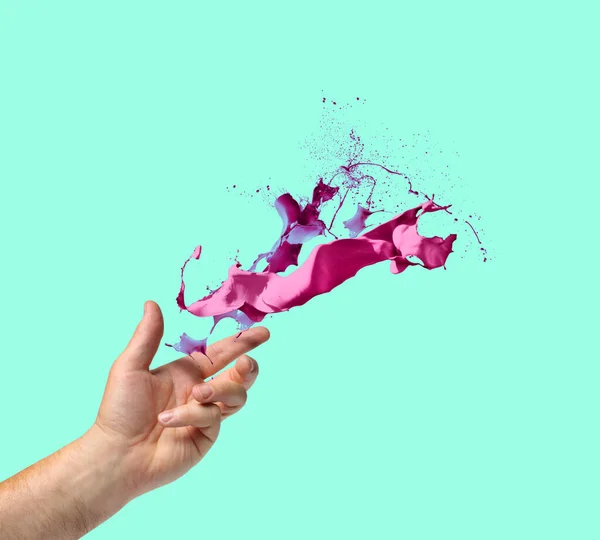 創造性の概念の手はターコイズブルーの背景にピンクと紫の塗料のスプラッシュを投げる — ストック写真