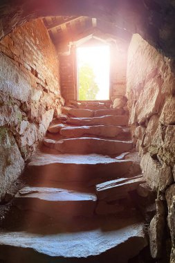 Karanlık mahzen zindanının dik taş merdivenleri, gün ışığı, umut ve özgürlük kavramı.