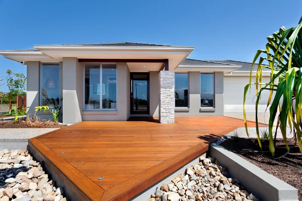 Patio de madera con grandes rocas alrededor de una mansión moderna — Foto de Stock